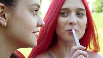 Deux belles filles fumant une cigarette électronique iqos dans un parc d'été