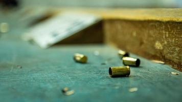 Empty pistol bullet shells on wooden table in a shooting range photo