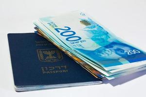 Stack of israeli money bills of 200 shekel and israeli passport photo