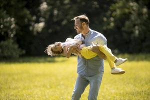 Padre con hija divirtiéndose en el césped del parque foto