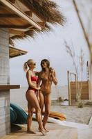 Young women in bikini standing by the surf cabin on a beach at summer day photo