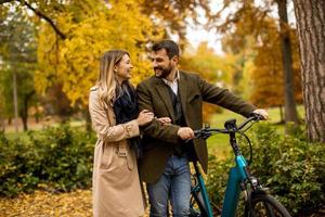 Young couple in the autumn park with electrical bicycle photo