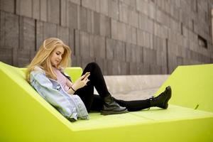 Young woman sitting in the city and use a mobile phone photo