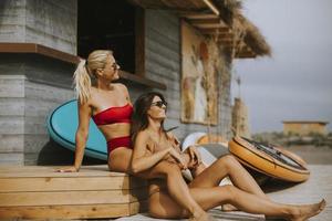 Young women in bikini sitting by the surf cabin on a beach at summer day photo
