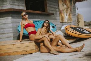 Young women in bikini sitting by the surf cabin on a beach at summer day photo