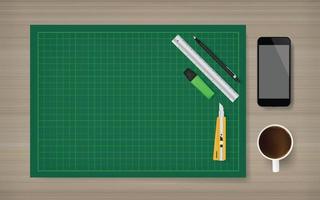 Estera de corte verde con conjunto de objetos de oficina: cortador, regla, lápiz, teléfono inteligente y taza de café sobre fondo de madera. ilustración vectorial.