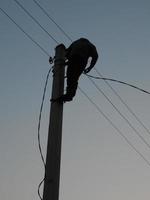 Electrician works in special clothes on the pole photo