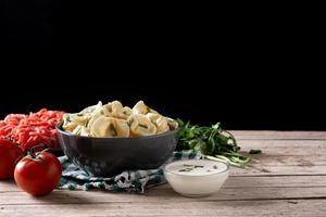 bolas de masa hervida pelmeni en mesa de madera. comida tipica rusa foto