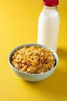 Corn flakes in a blue bowl and milk bottle photo