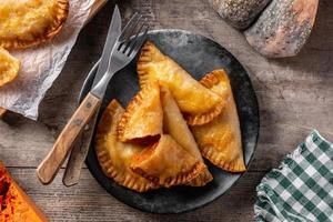 Pumpkin empanadillas on wooden table. Autumn food photo