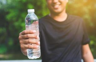 joven corredor de fitness hombre bebiendo una botella de agua. foto