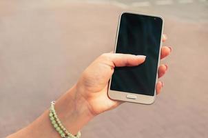 mano femenina que sostiene el teléfono inteligente con pantalla en blanco foto
