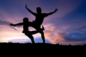 silueta feliz saltando contra hermosa en la puesta de sol. libertad, concepto de disfrute foto