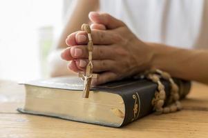 person praying with rosary holy book photo