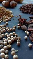 Photo of some cooking ingredients such as white pepper, pepper, nutmeg, cloves on black background