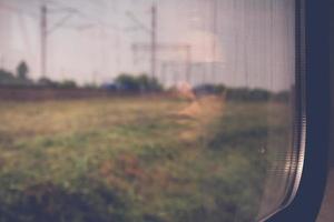 Cara de mujer misteriosa con gafas de sol negras reflejadas en la ventana de un tren que viaja foto