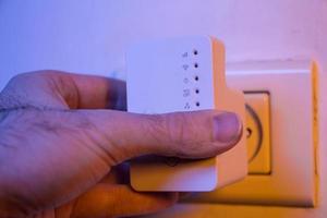 Man insert WiFi repeater into electrical socket on the wall photo