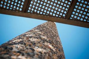 Low angle view on wooden shade of seating bench with pebble stone column photo