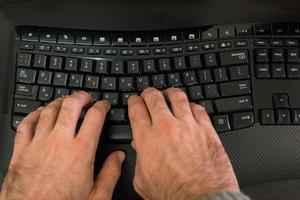 Hombre escribiendo en un teclado con letras en hebreo e inglés foto