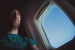 Pensive man seat by the window of an airplane photo