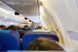 Interior del avión de pasajeros con personas en los asientos.