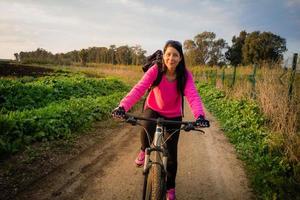 Woman riding a bicycle in the countryside and looking at camera photo