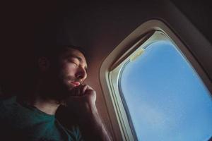 Young man resting and sleeping on an airplane photo