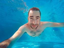 joven apuesto hombre de buceo bajo el agua en una piscina foto