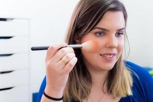 Woman applying makeup in her bedroom photo