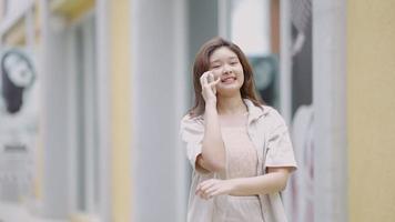 Adolescente asiática hablando por teléfono con sus amigos en el centro comercial video
