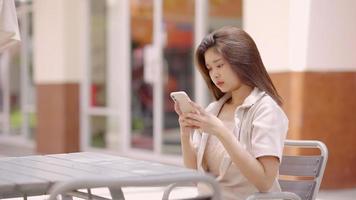 Asian teenage girl talking on the phone with her friends at the shopping mall video