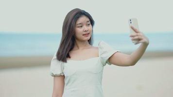 asiatisk tjej som tar selfies med sin mobiltelefon på stranden video