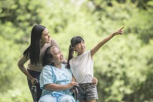 Happy grandmother in wheelchair with her daughter and grandchild in a park, Happy life Happy time. photo