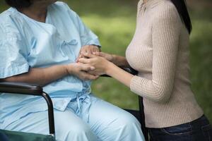 Granddaughter talking with her grandmother sitting on wheelchair, cheerful concept, happy family photo