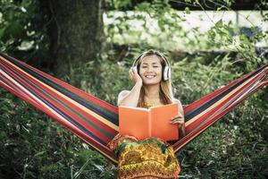 Beautiful happy young woman with headphones listening to music and reading a book photo