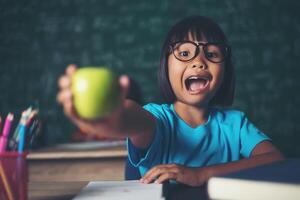 girl holding a apple in the classroom photo