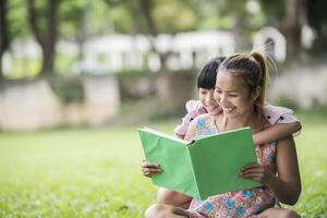 Mother and daughter reading a fairytale to her daughter in the park photo