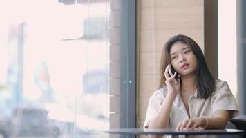 Adolescente asiática hablando por teléfono con sus amigos en el centro comercial video