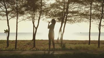 Aziatisch meisje dat zich uitstrekt op het strand met ochtendlicht video