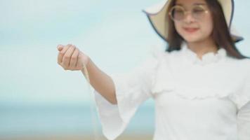 menina asiática soltando lentamente a areia da mão na praia