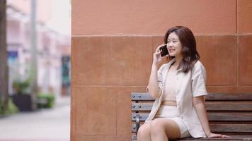 Aziatische tienermeisje praten aan de telefoon met haar vrienden in het winkelcentrum video
