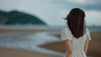 uma linda garota asiática está caminhando na praia à beira-mar video