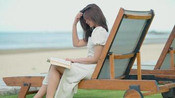 adolescente asiática lendo um livro na praia