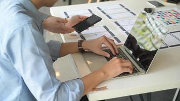 The UX team is designing an application for smartphones with a laptop in a modern office. photo