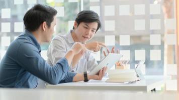 A Two young business professionals are discussing their future projects with a comfortable laptop on the desk in the office. photo