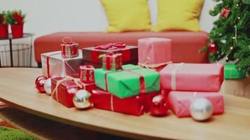 caixa de presente de natal sobre a mesa e enfeites de luzes o natal comemora o ano novo na sala de estar em casa. video