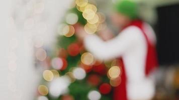 Fondo borroso Hombre asiático con caja de regalo pequeña Navidad decorar árbol de Navidad celebra el año nuevo en la sala de estar. video