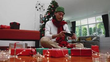 hombre asiático que usa el móvil tomando una caja de regalo de foto. video