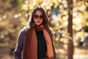 Young woman with long hair and sunglasses in autumn forest photo