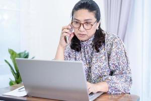 mujer de negocios asiática trabajar desde casa comunicarse con la oficina por videollamada de conferencia en la computadora portátil, quedarse en casa.